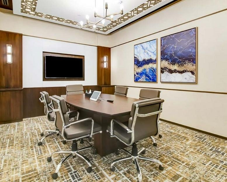 Modern boardroom at Parinee Crescenzo featuring a large dark wood table and blue abstract paintings.