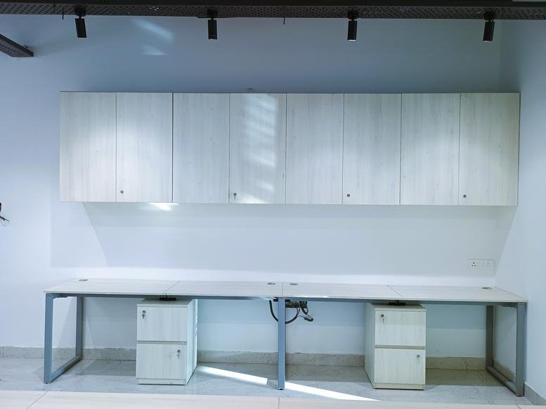 Wide view of a long office workstation with under-desk pedestals and wall cabinets.