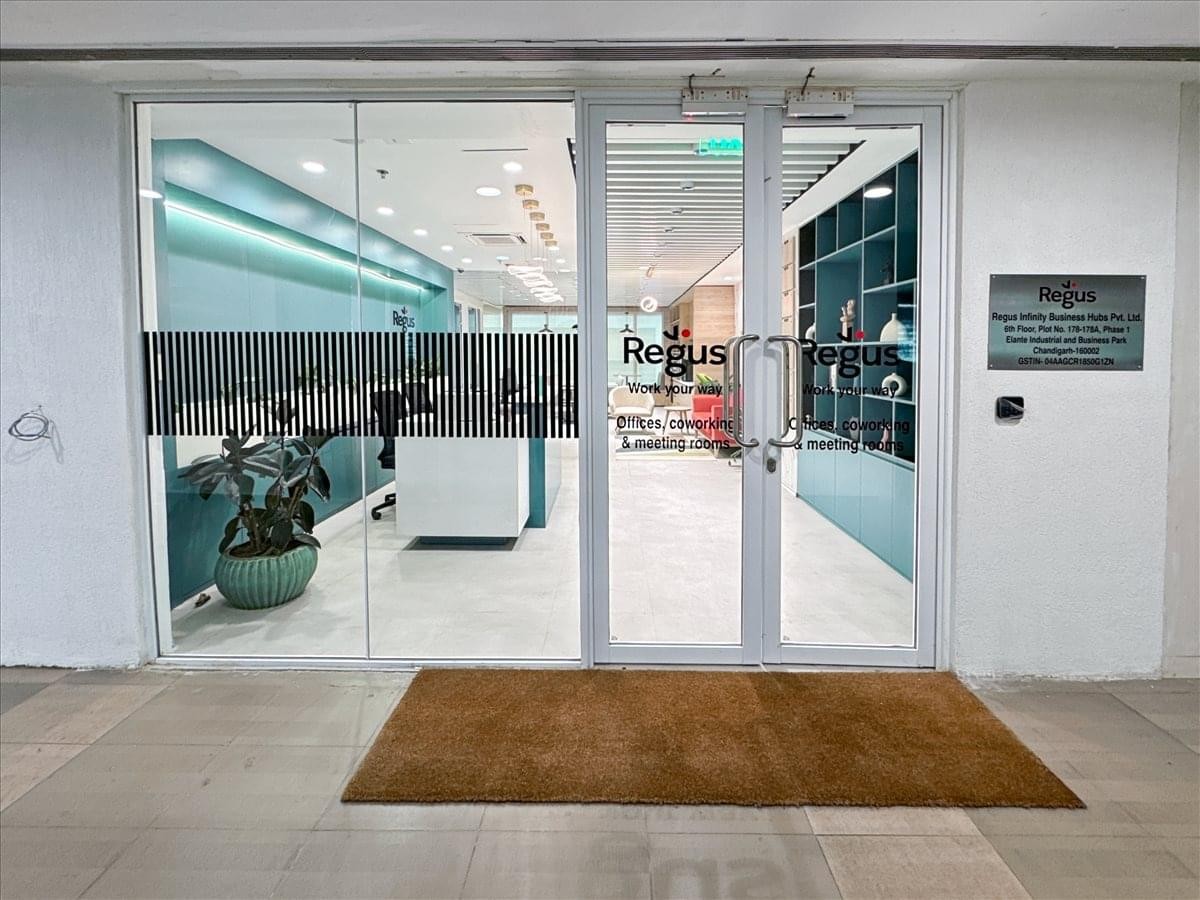 Glass entrance to the Regus office at Elante Mall, Chandigarh, showing the reception area inside.