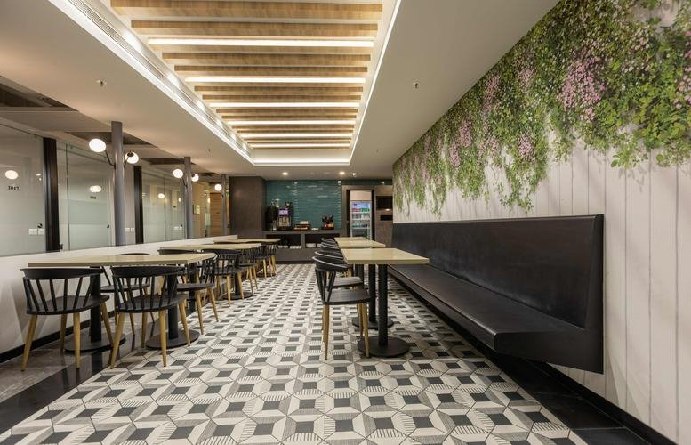 Modern dining area featuring patterned floor tiles, wooden tables, and a green plant wall.