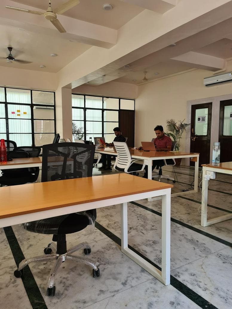 Spacious open-plan coworking area with natural light and marble flooring.