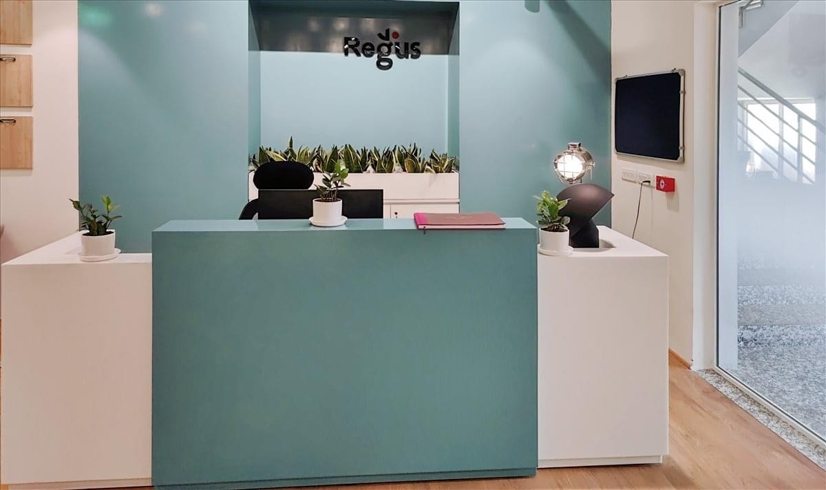 Modern reception desk at Regus Tower with teal accent walls and indoor plants.