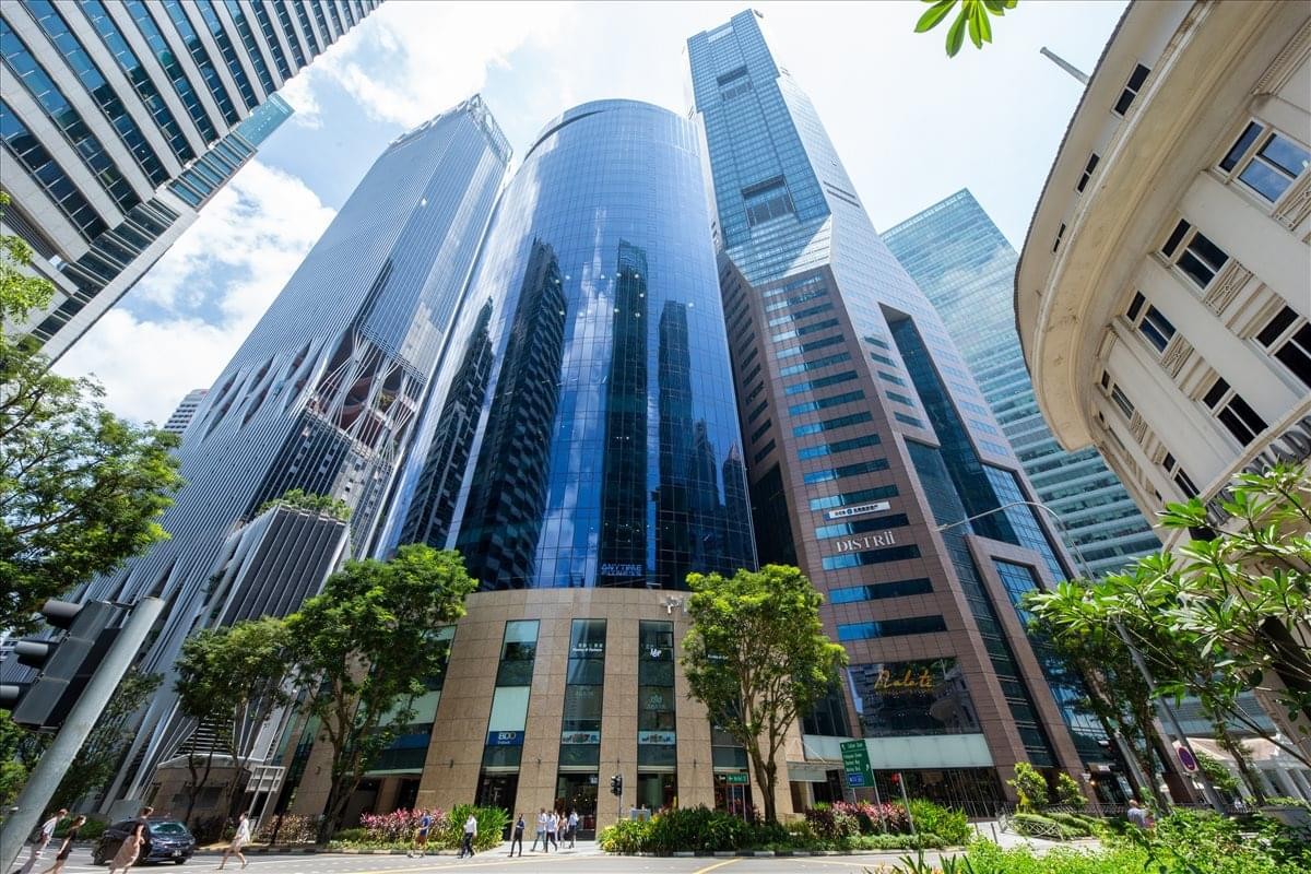A low-angle view of the towering glass facade of the PLUS Building in Singapore.