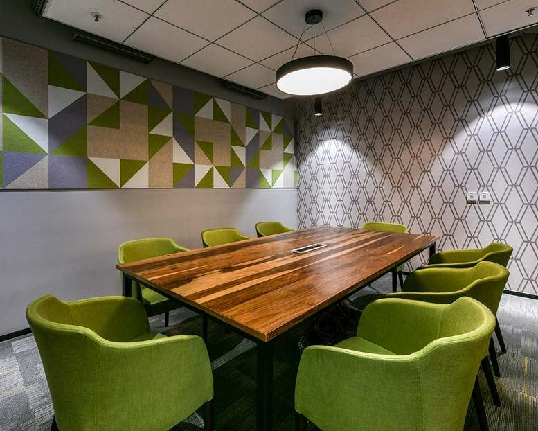 Spacious meeting room at Prestige Phoenix with a natural wood table and vibrant green armchairs.