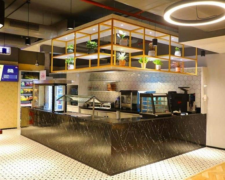 Modern café and breakout area at Prestige Shantiniketan with a marble counter and hanging plants.