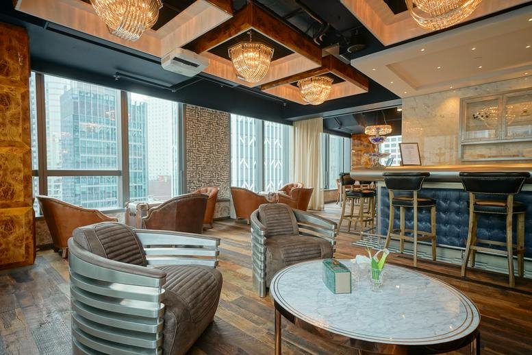 Elegant lounge at Prosperity Tower with chandeliers, plush armchairs, and a bar counter.