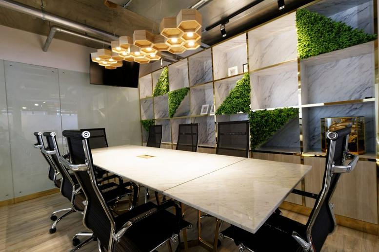 Meeting room at PS Tower with a marble table, ergonomic chairs, and a geometric honeycomb light fixture.