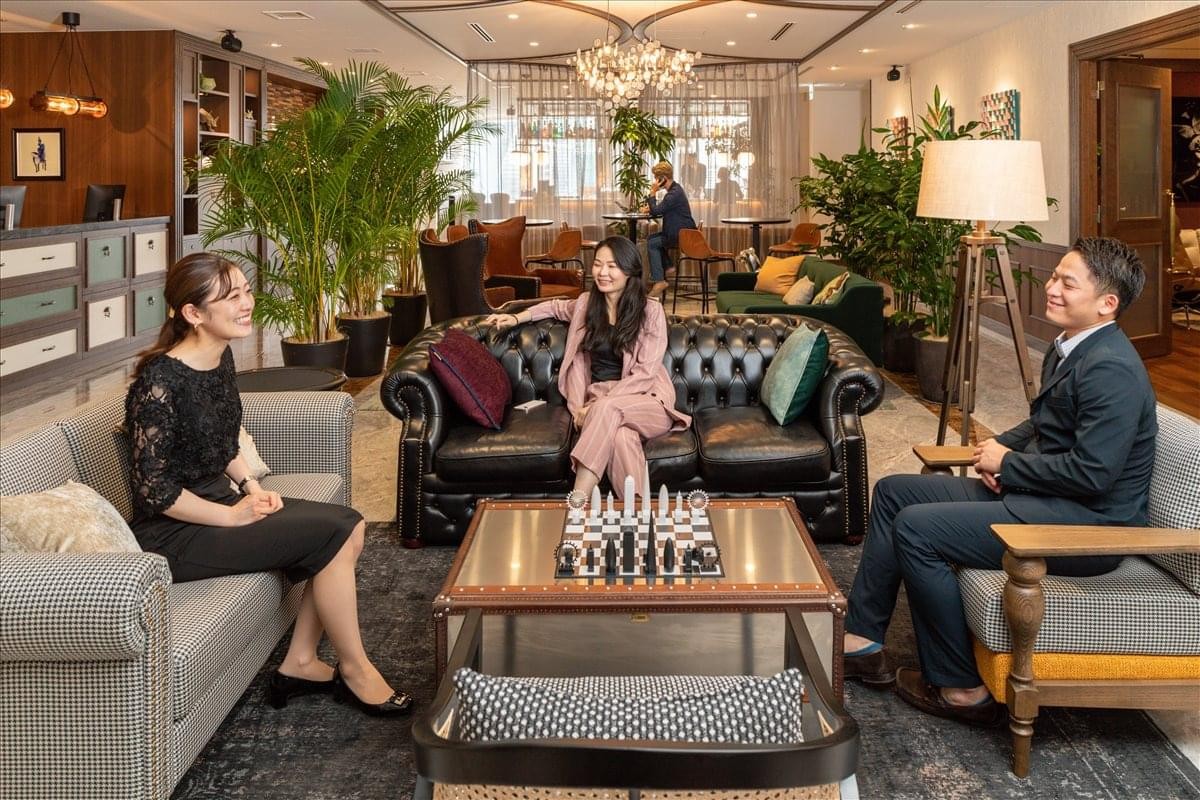 Large communal lounge at Roppongi Hills Mori Tower 11F featuring leather sofas, a chess set, and lush greenery.