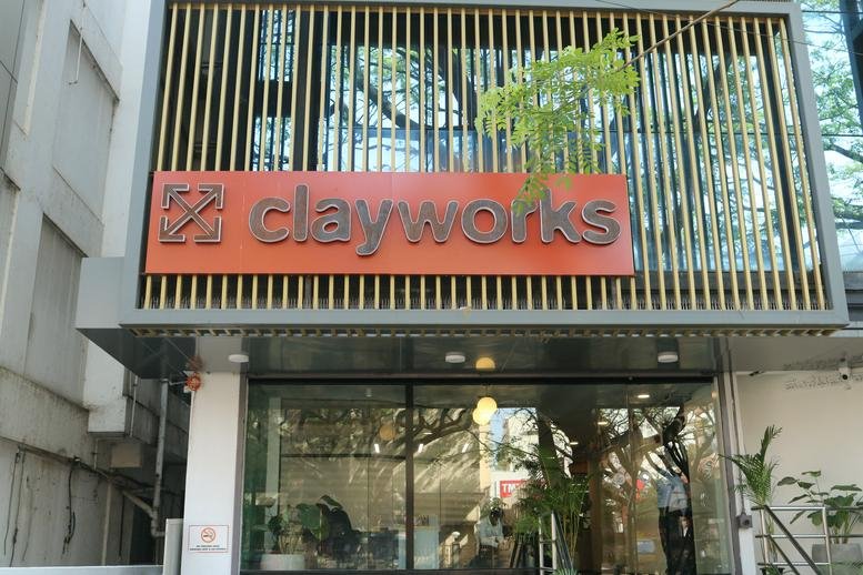 Entrance of the building with Clayworks sign and greenery.