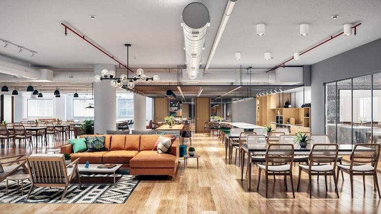 Bright, spacious communal lounge at Sai Radhe Complex featuring an orange sectional and wooden dining tables.