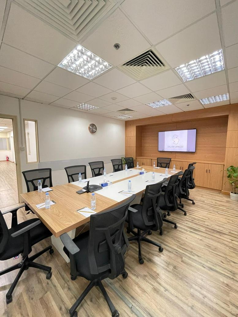 Spacious boardroom at Salam Spaces, King Fisal road, Yarmook with a large wooden table and wall-mounted screen.