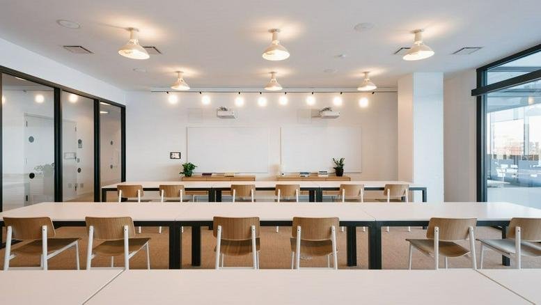 Spacious meeting room with white tables and wooden chairs at Sannomiya Plaza East.