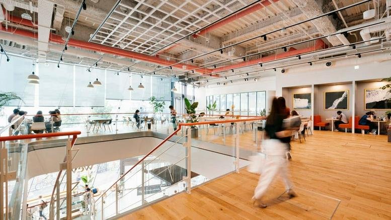Spacious communal lounge at Sannomiya Plaza East featuring warm wood floors and high industrial ceilings.
