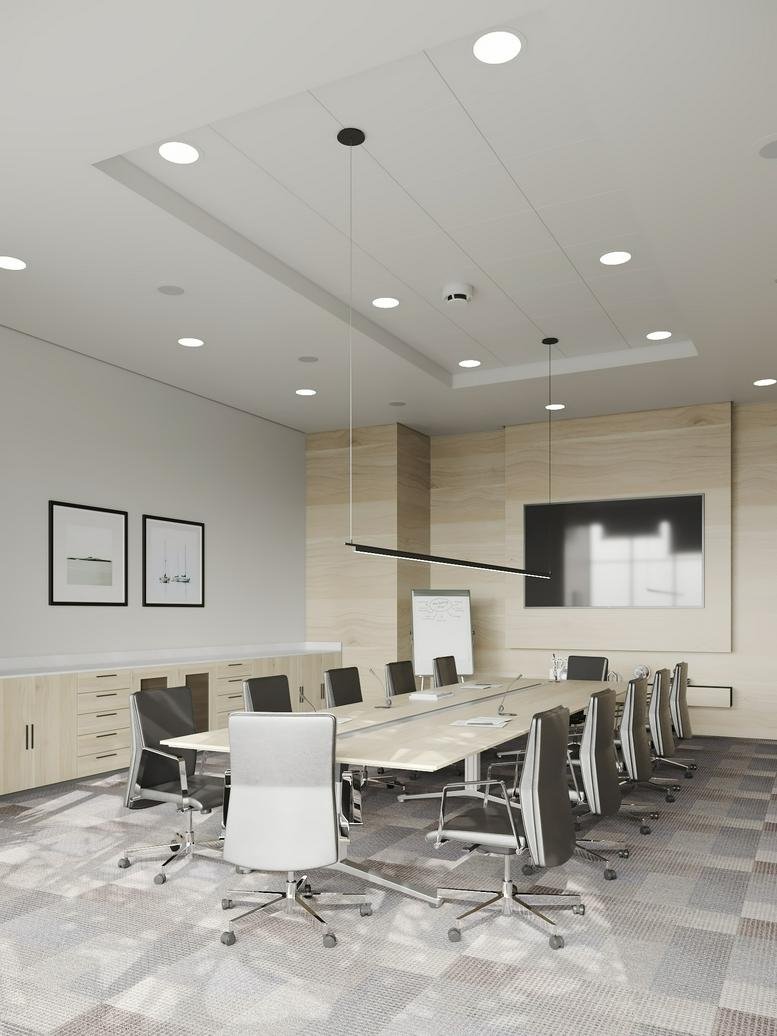 Modern conference room with a long boardroom table, stylish pendant lighting, and neutral-toned carpet.