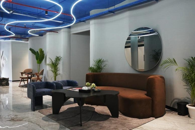 Modern lounge area at SCO 142, 143, 144, 1st Floor, Sector 17C, Chandigarh with a brown sofa and blue ceiling.