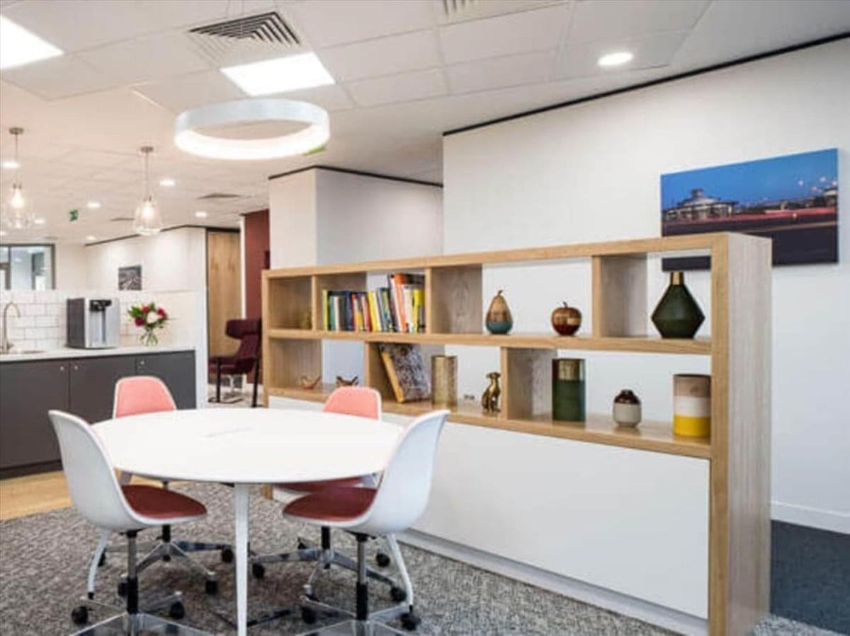 Communal breakout area at Sheikh Rashid Tower with a round table, bookshelf, and modern lighting.