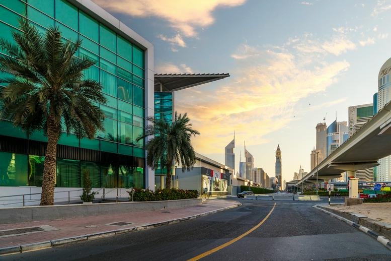 Exterior street view of the glass-facade building near Sheikh Zayed Road during sunset.