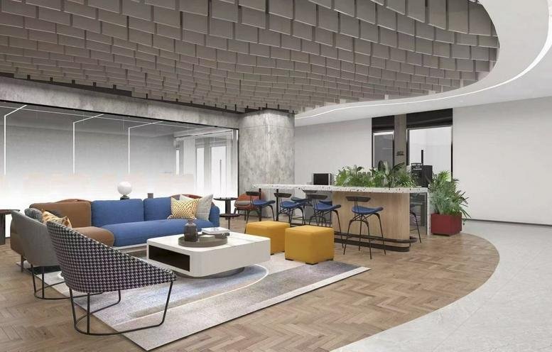 Large breakout space featuring a blue sofa, yellow ottomans, and a sculptural acoustic ceiling.