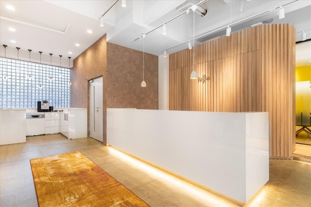 Bright reception area with a white front desk and vertical wood slat feature wall.