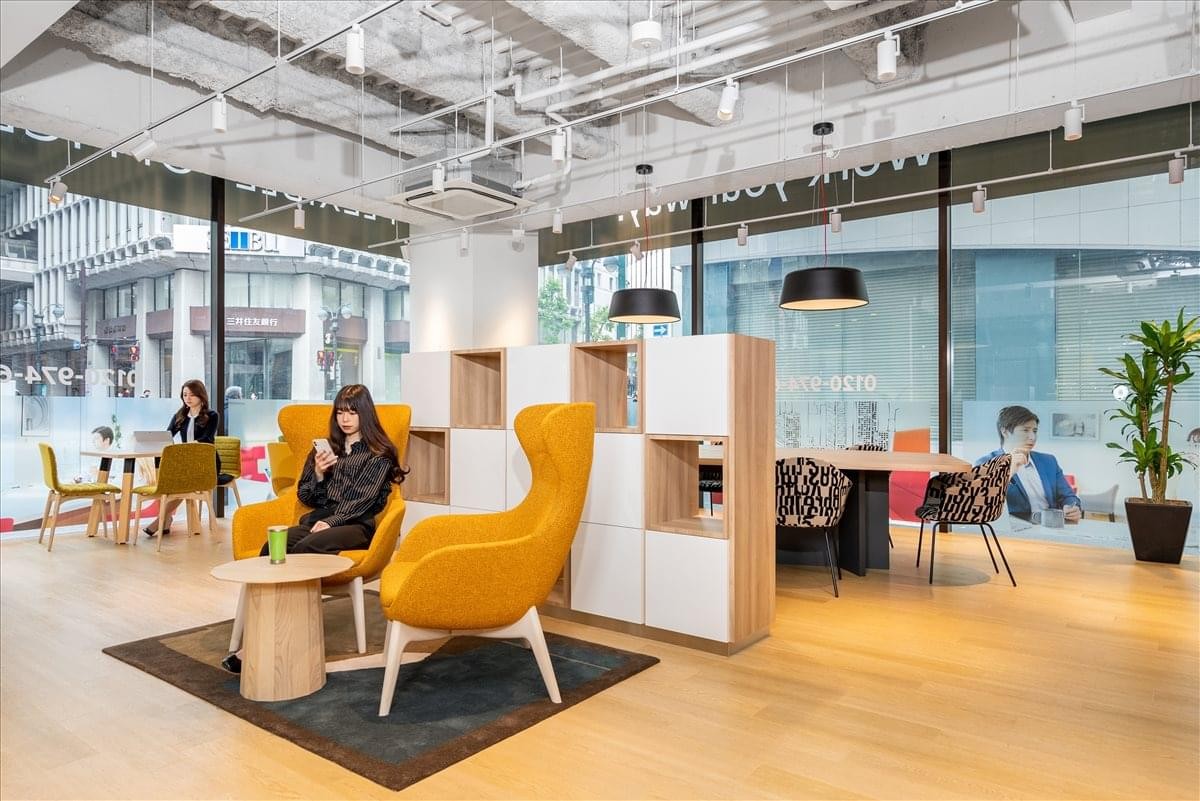 Lounge area with stylish yellow armchairs, wooden dividers, and floor-to-ceiling windows.