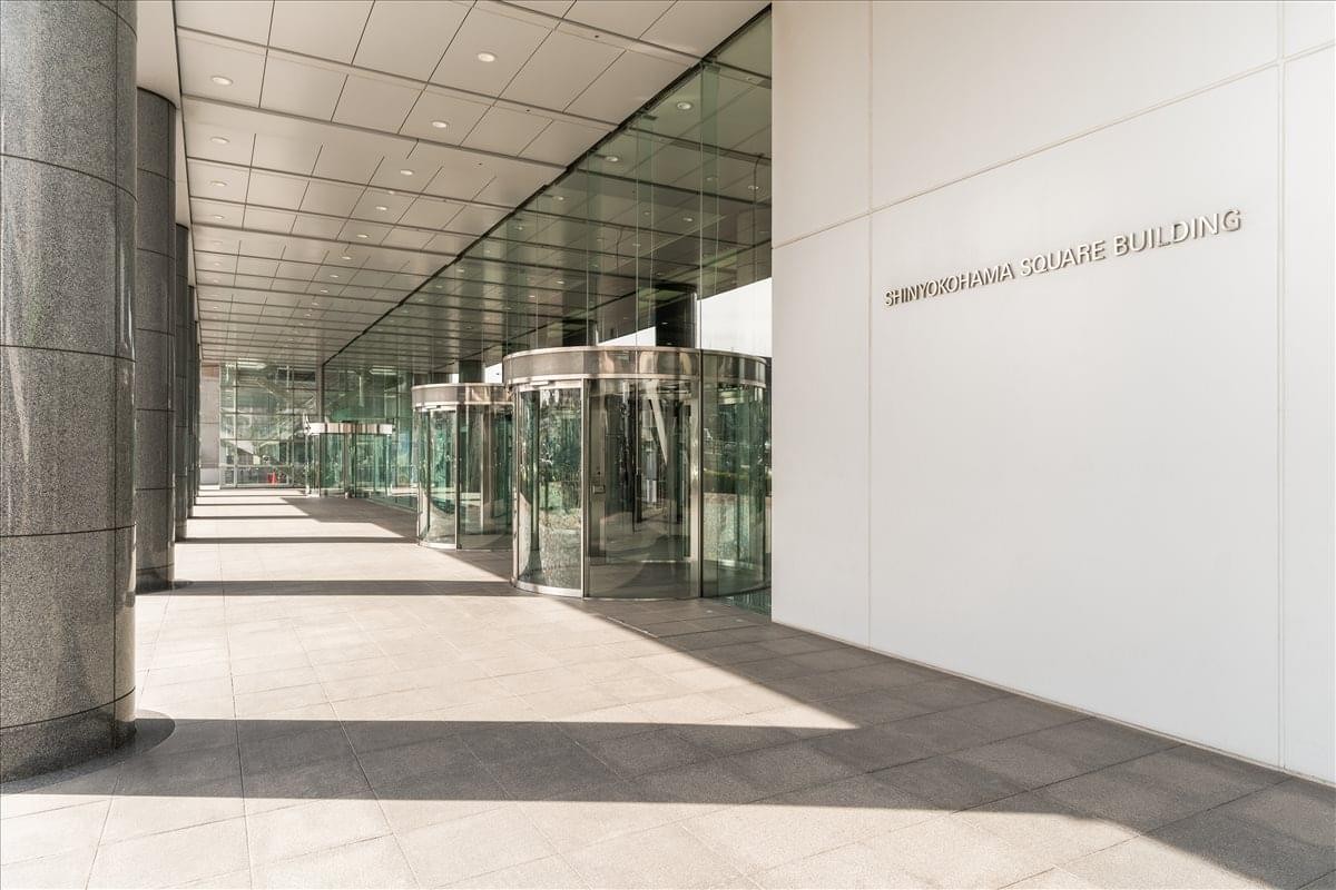 Modern glass entrance of the Shin Yokohama Square building under a covered walkway.
