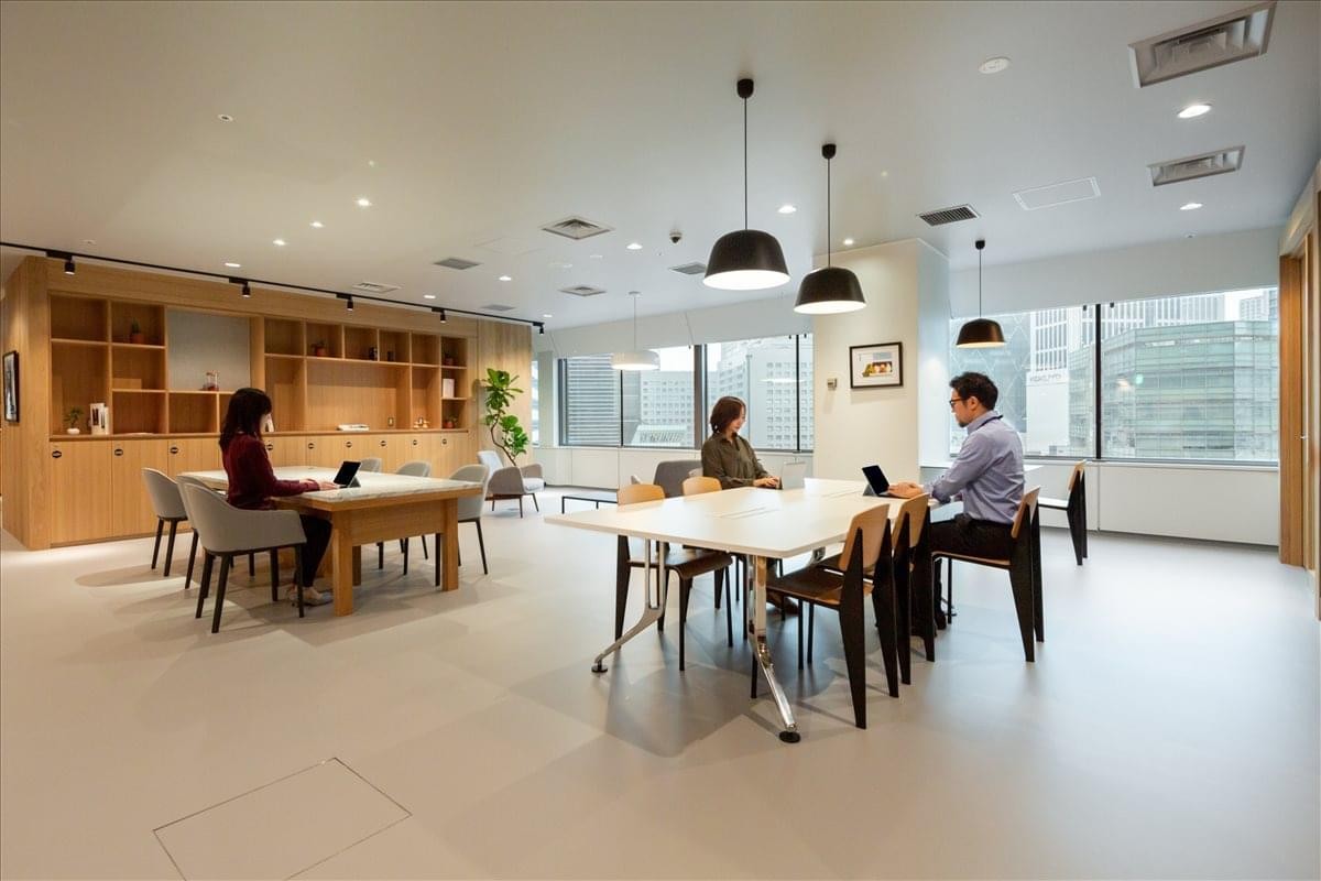 Communal breakout area with wood shelving and modern pendant lighting.