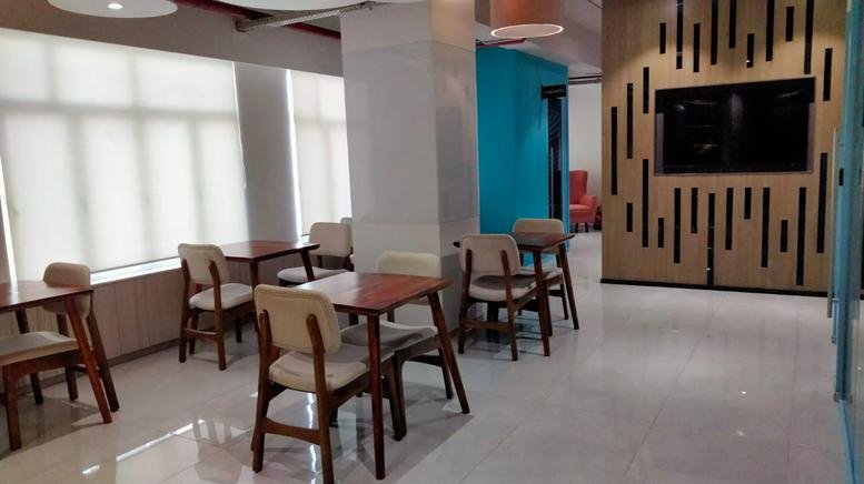Bright dining area with wooden tables and chairs near a turquoise feature wall.