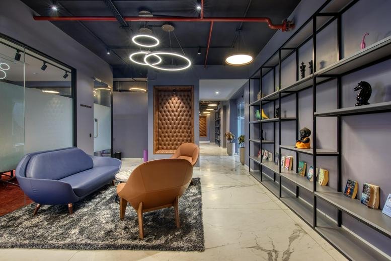 Spacious reception lounge at Shivarth The Ace with modern seating and an ornate wood-carved feature wall.
