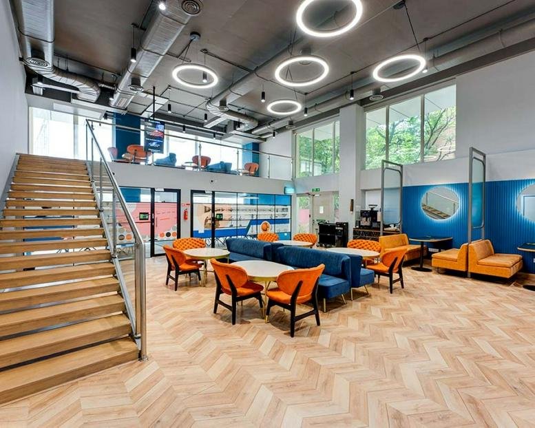 Bright lobby and lounge at Soul Space Paradigm with a staircase, blue sofas, and circular lights.