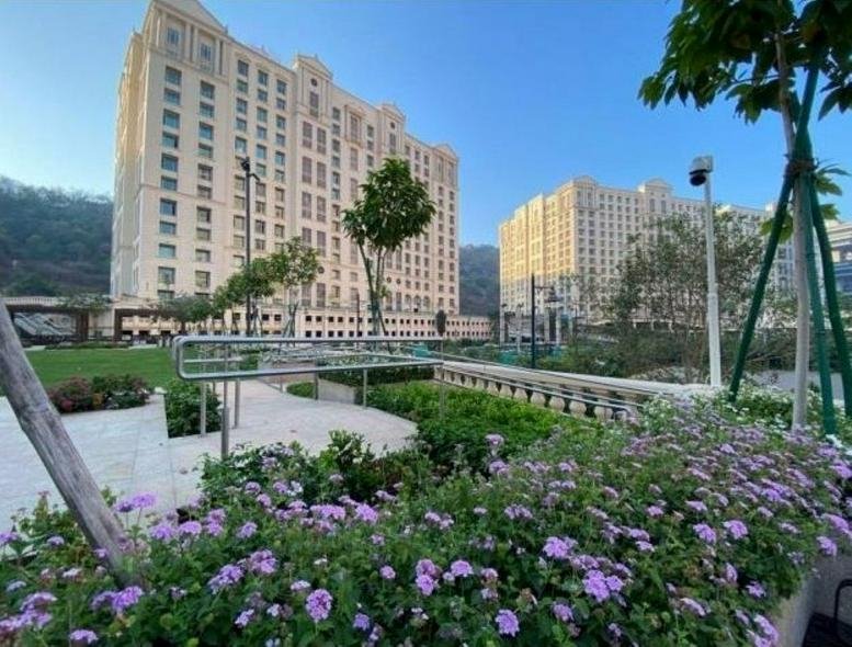 Exterior view of the ornate Winchester building at Hiranandani Gardens with lush purple flowerbeds.