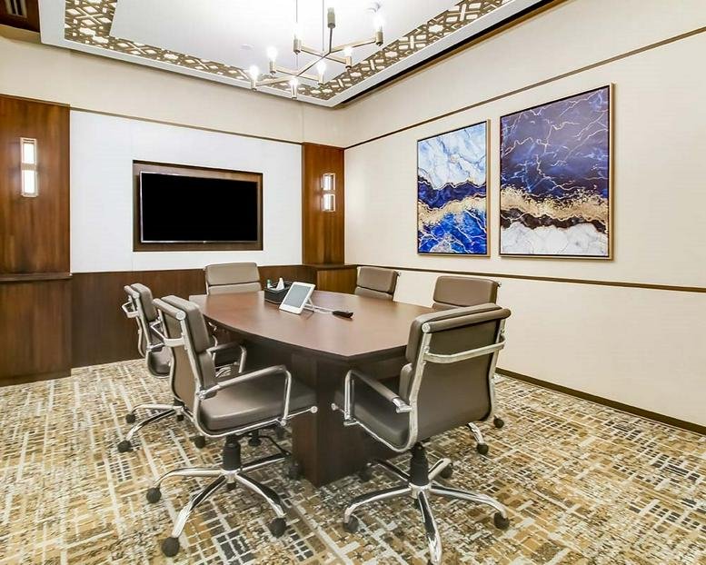 Elegant boardroom at Spero Primus, SIDCO Industrial Estate, with a large wooden table and blue abstract art.
