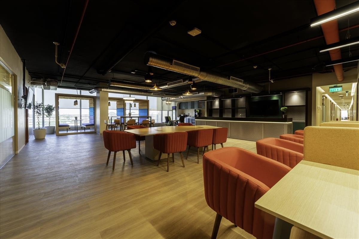 Spacious communal lounge at Spring Plaza with diverse seating, wooden floors, and a modern open ceiling.
