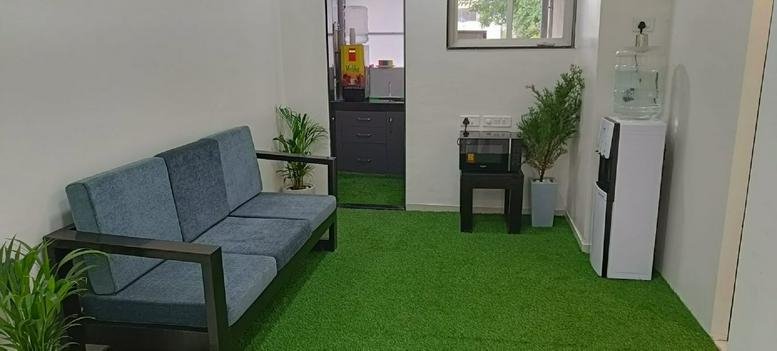 Breakout area at Suman Ankur with green turf flooring and blue sofa.