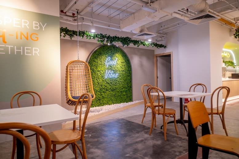 Spacious coworking lounge with a green moss feature wall and hanging chair at Sunway Putra Mall.