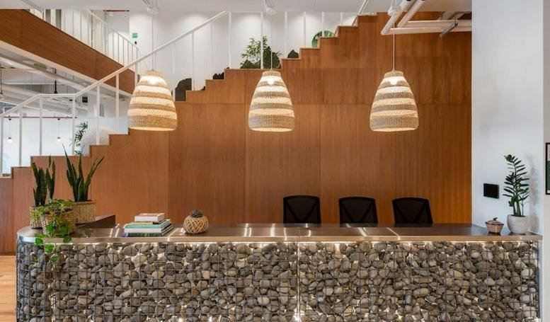 Modern stone-fronted reception desk with hanging wicker pendant lights at Kalyani Roshni Tech.
