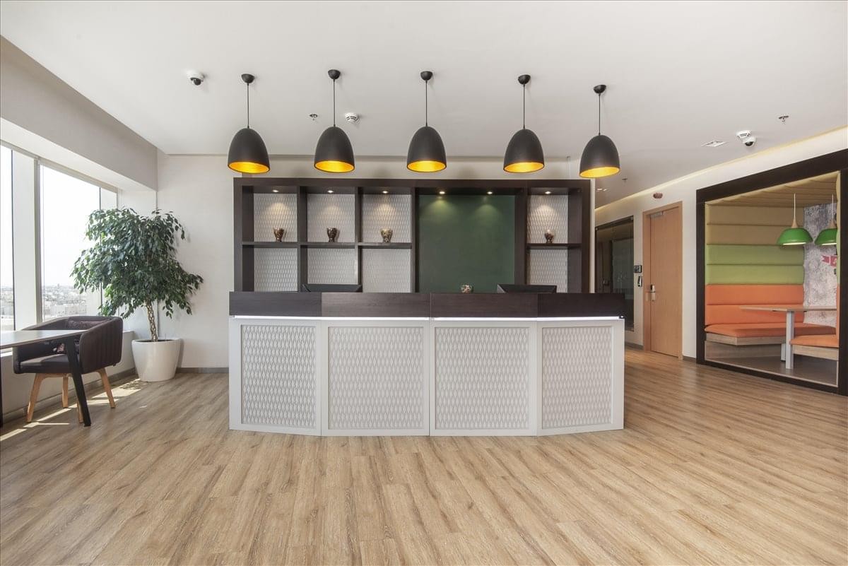 Reception area featuring a white front desk, wooden floors, and modern pendant lighting.