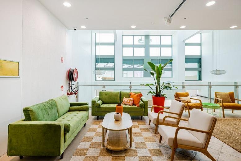 Bright common lounge at Tenancy 6001/6002, Robina Town Centre Drive, featuring green velvet sofas and a checkered rug.