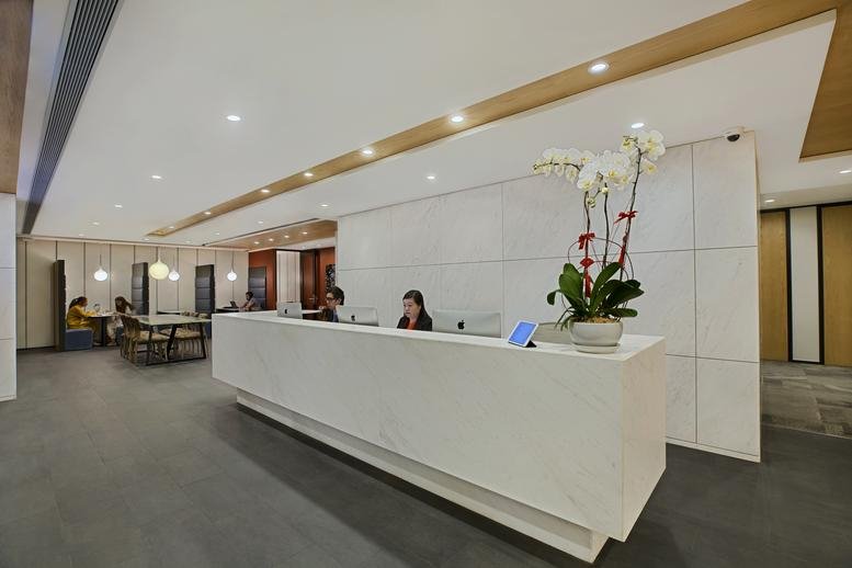 Bright, modern reception area at The Hong Kong Club Building with a white marble desk.