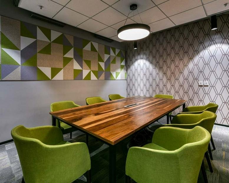 Modern meeting room at The Empire Tower with a large wooden table and lime green armchairs.