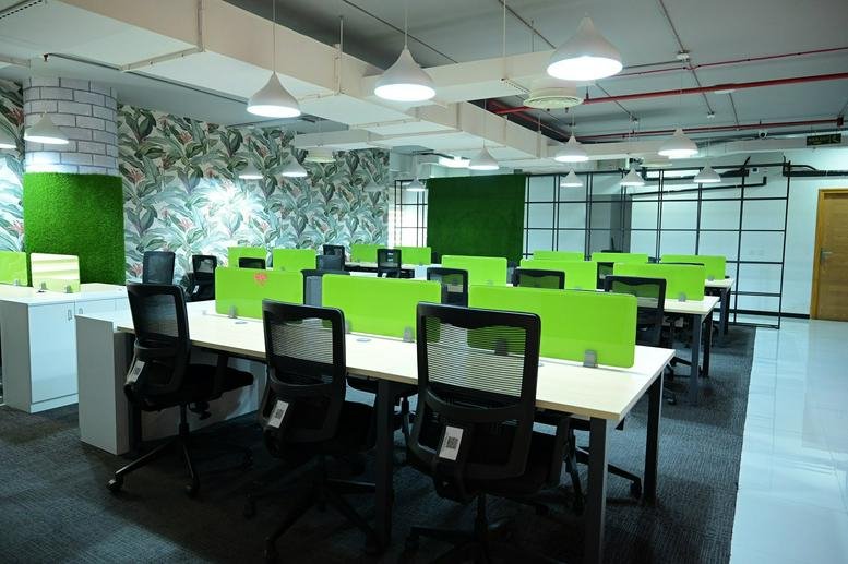 Spacious open-plan workspace at The First building with vibrant green accents and patterned wallpaper.
