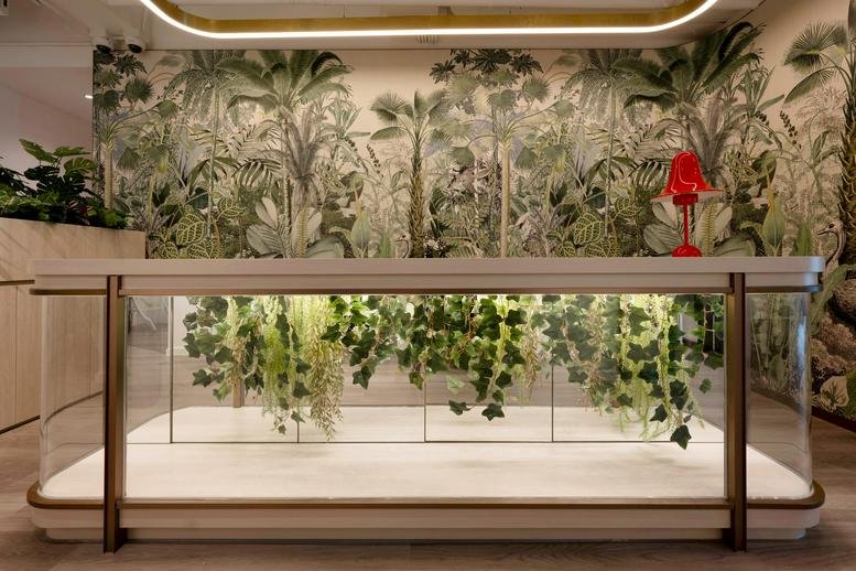 Reception area at The Garden Offices, 25 Tung Lo Wan Road featuring a glass desk with plants and tropical mural.