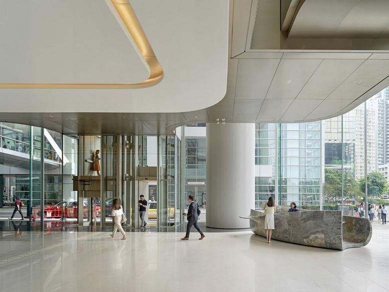 A bright, high-ceilinged building lobby with marble floors and floor-to-ceiling windows.
