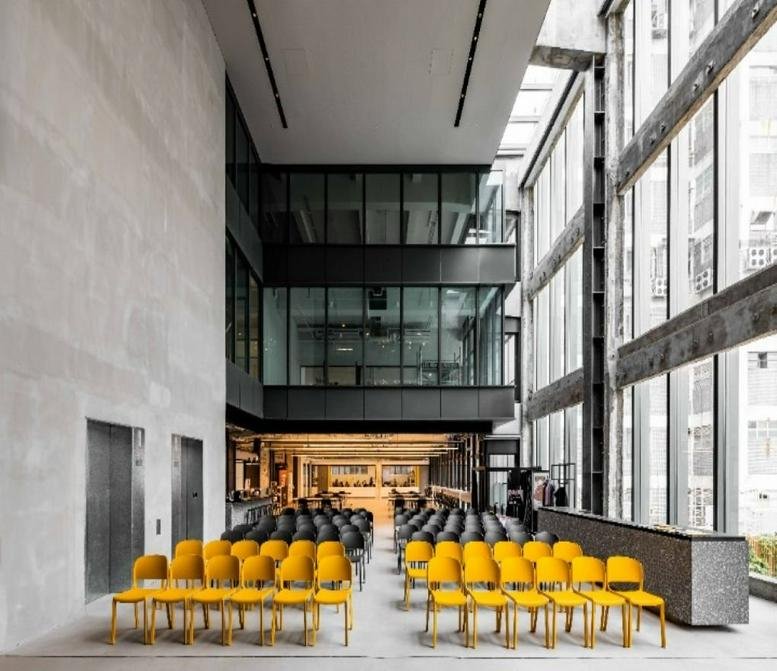 Spacious event hall at The Mills with rows of bright yellow and grey chairs under a high industrial ceiling.