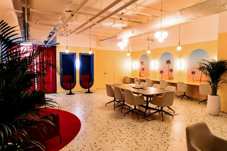 Spacious coworking lounge at The One Tower, Sheikh Zayed Road, Dubai featuring palm tree murals and warm lighting.