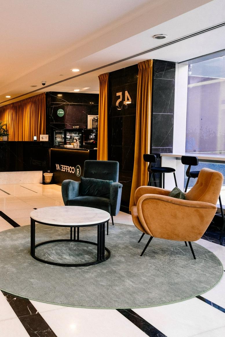 Chic lounge area with dark teal and mustard velvet armchairs on a circular grey rug.