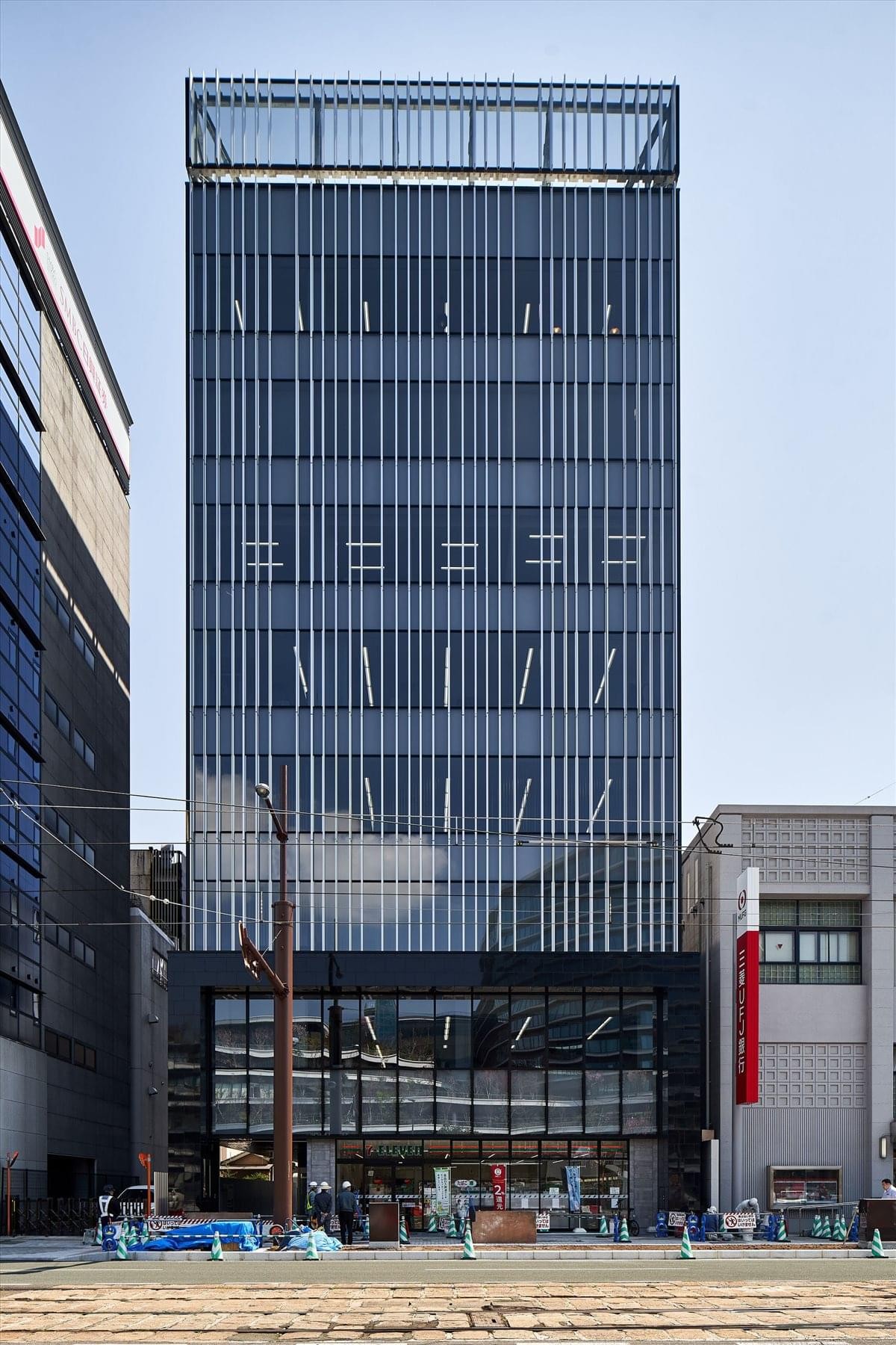 Full exterior view of The Place, Hanabata, Shinshigai, Chuo-ku, Kumamoto-shi, a modern glass-facade building.