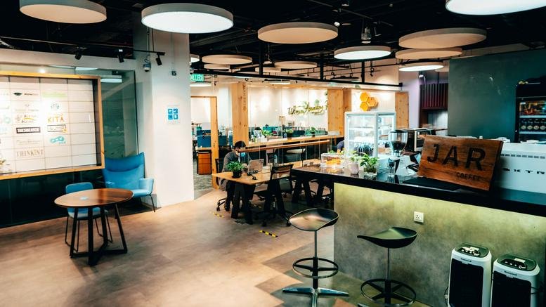 Cafe-style breakout area at The Starling Mall with a coffee bar and round wooden tables.