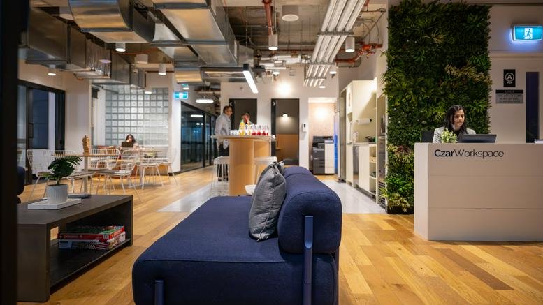 Spacious communal lounge and reception area at The Trustees Building with wooden floors and a green feature wall.