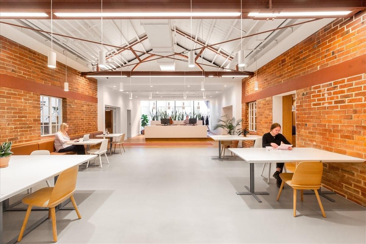 Spacious open-plan coworking area with brick walls and exposed timber trusses at The Wentworth Building.