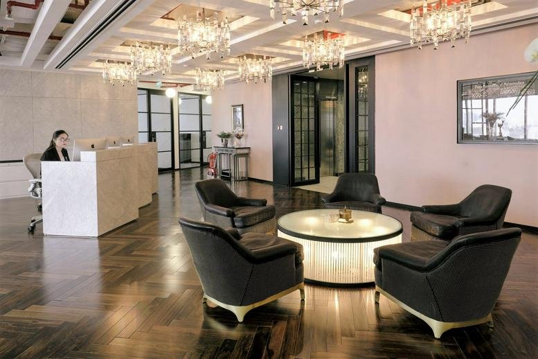 Spacious reception area with crystal chandeliers, dark wood flooring, and elegant seating.